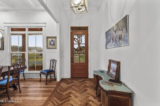 entryway with an inviting chandelier, parquet flooring, and crown molding