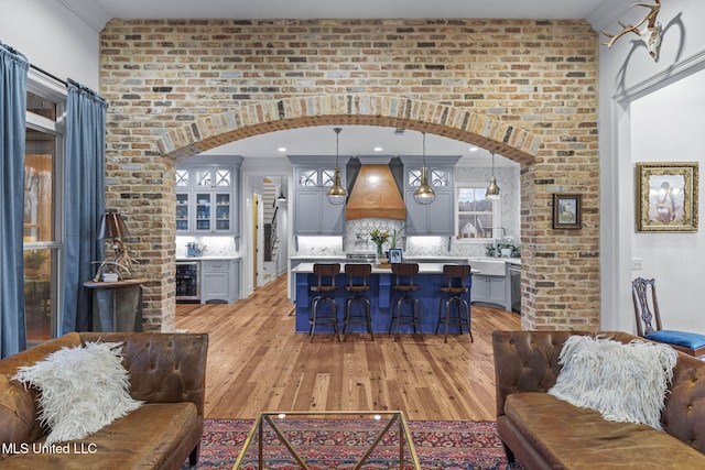 interior space featuring hanging light fixtures, custom exhaust hood, gray cabinetry, and beverage cooler