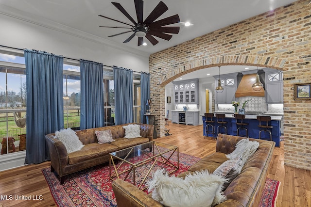 living room featuring crown molding, hardwood / wood-style flooring, ceiling fan, brick wall, and beverage cooler