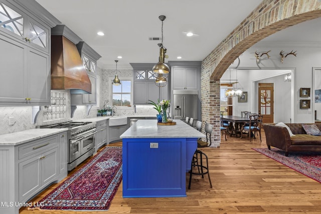 kitchen featuring hanging light fixtures, premium appliances, ornamental molding, custom range hood, and a kitchen island