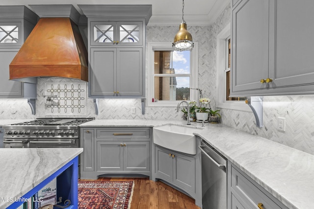 kitchen featuring sink, dishwasher, premium range hood, hanging light fixtures, and light stone counters