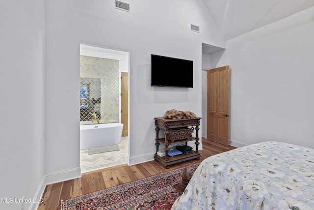 bedroom featuring hardwood / wood-style flooring, connected bathroom, and vaulted ceiling