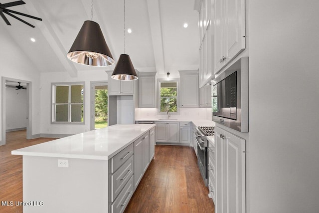 kitchen featuring pendant lighting, a center island, vaulted ceiling with beams, dark hardwood / wood-style floors, and stainless steel appliances