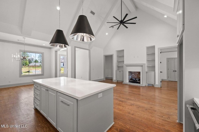 kitchen featuring hanging light fixtures, beamed ceiling, high vaulted ceiling, dark hardwood / wood-style floors, and a kitchen island