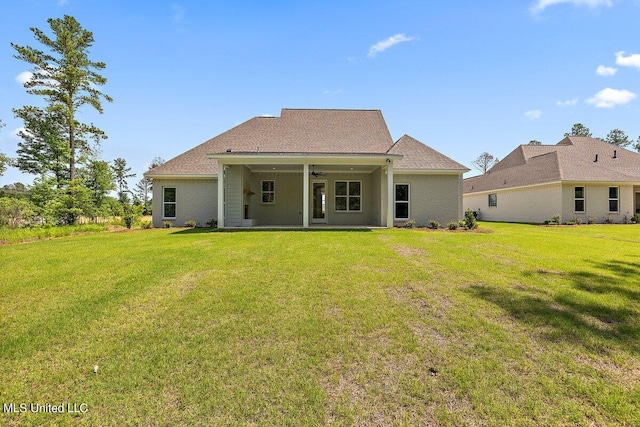 back of property with ceiling fan and a yard