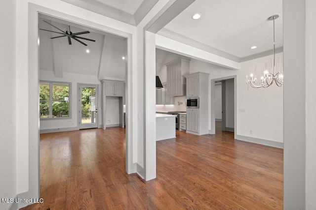 unfurnished living room featuring vaulted ceiling with beams, dark hardwood / wood-style flooring, and ceiling fan with notable chandelier