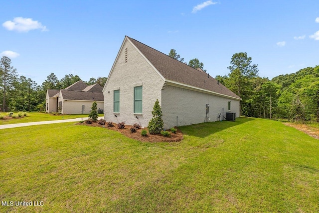 view of side of property featuring central AC unit and a yard