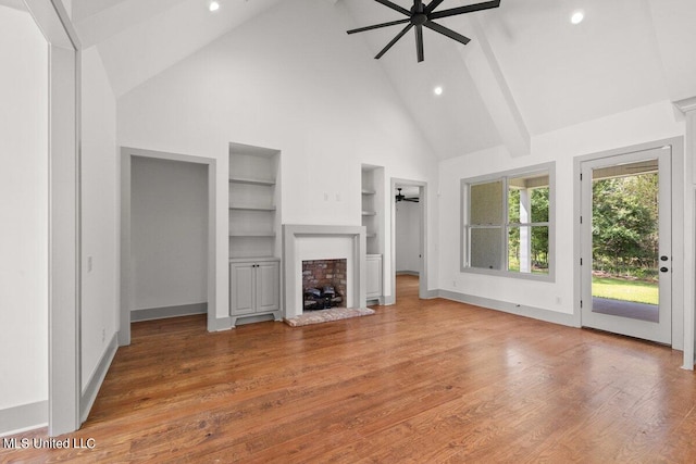 unfurnished living room featuring high vaulted ceiling, ceiling fan, built in shelves, beamed ceiling, and wood-type flooring