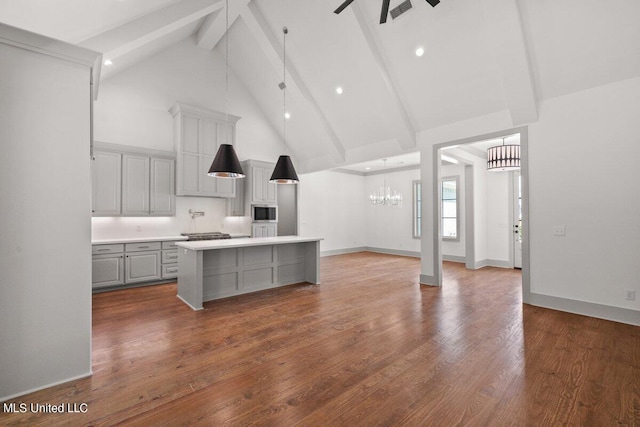 kitchen featuring stainless steel microwave, a center island, dark hardwood / wood-style flooring, beamed ceiling, and high vaulted ceiling