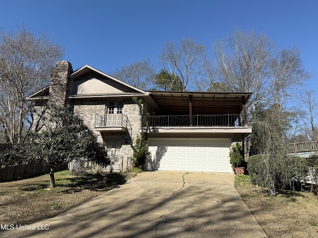 view of front facade featuring a balcony, a garage, a chimney, and concrete driveway