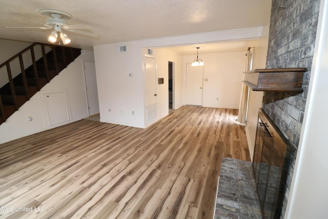 unfurnished living room featuring visible vents, ceiling fan, light wood-style flooring, and stairs