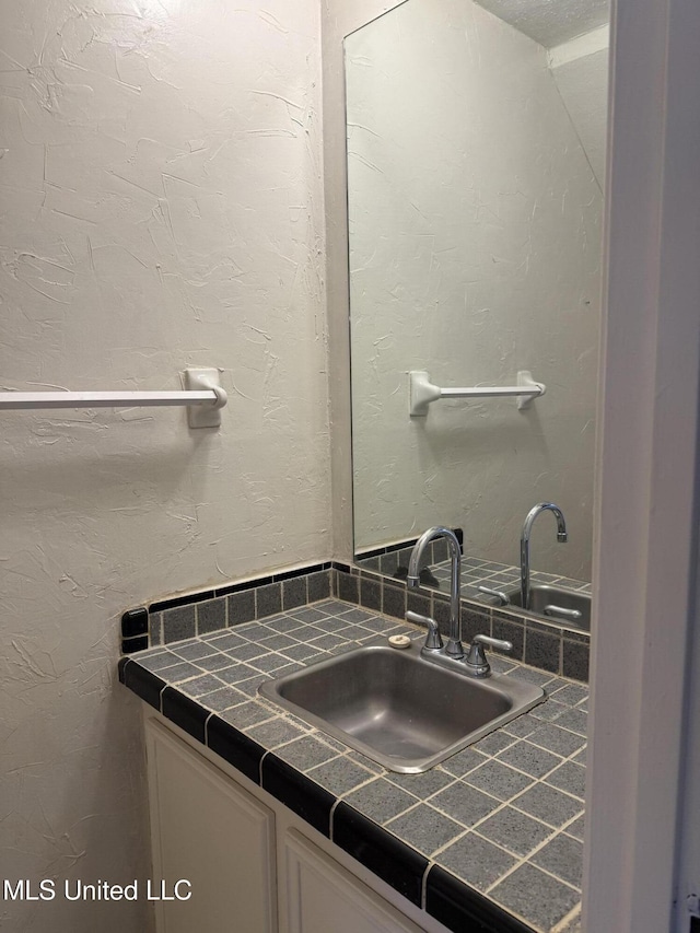 bathroom featuring a textured wall and vanity