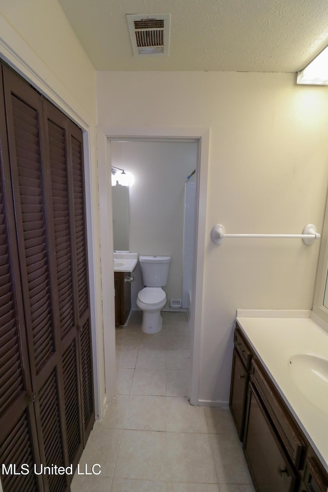 bathroom featuring a closet, visible vents, toilet, vanity, and tile patterned flooring