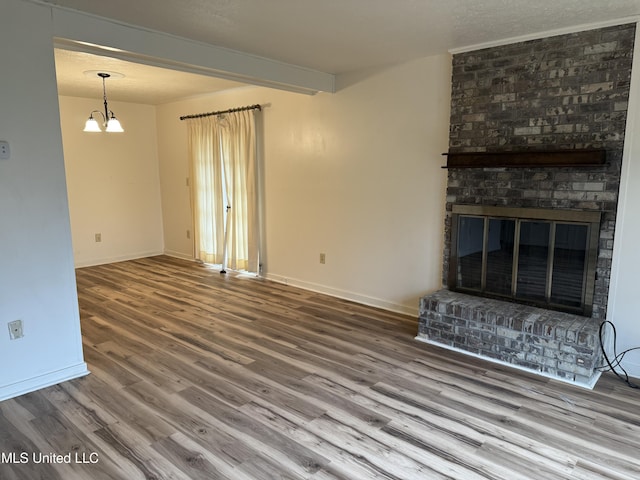 unfurnished living room with a fireplace, baseboards, wood finished floors, and beamed ceiling