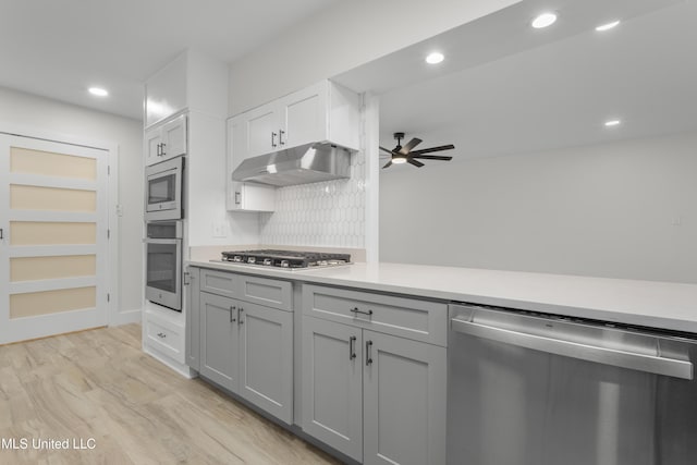 kitchen with stainless steel appliances, ceiling fan, light wood-type flooring, backsplash, and gray cabinets