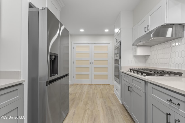 kitchen featuring stainless steel appliances, gray cabinetry, light hardwood / wood-style floors, and tasteful backsplash