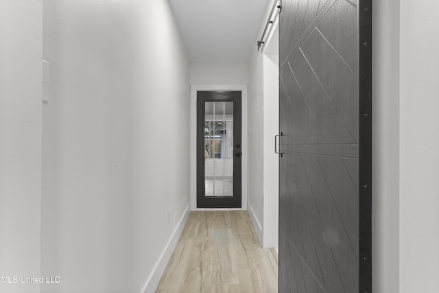 hall with light hardwood / wood-style flooring and a barn door