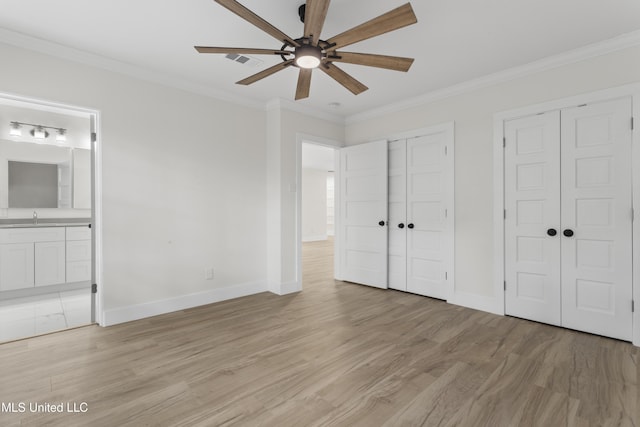 unfurnished bedroom with light hardwood / wood-style floors, crown molding, multiple closets, ceiling fan, and ensuite bathroom