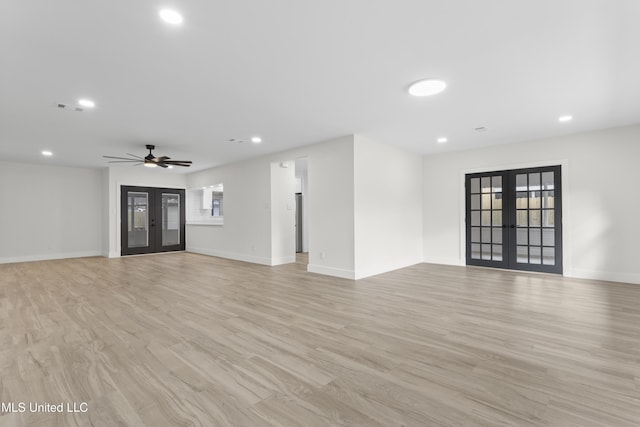 empty room with french doors, light wood-type flooring, and ceiling fan