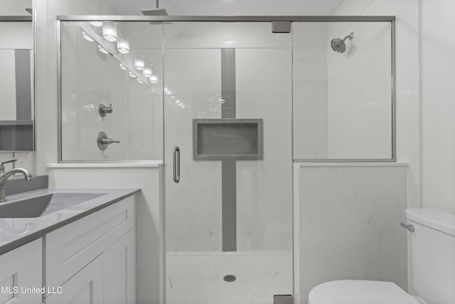 bathroom featuring toilet, a shower with door, and vanity