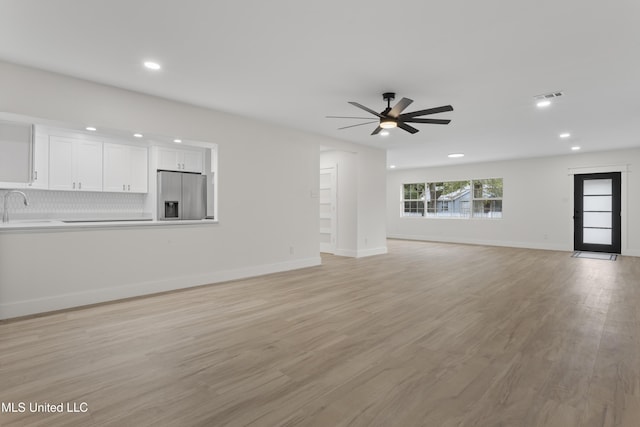 unfurnished living room featuring light wood-type flooring, ceiling fan, and sink