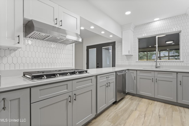 kitchen with sink, stainless steel appliances, decorative backsplash, gray cabinets, and extractor fan