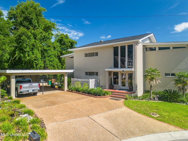 435 Christi Ln, Biloxi, MS 39531 - view of front of home with concrete driveway, a carport, brick siding, a front lawn, and french doors