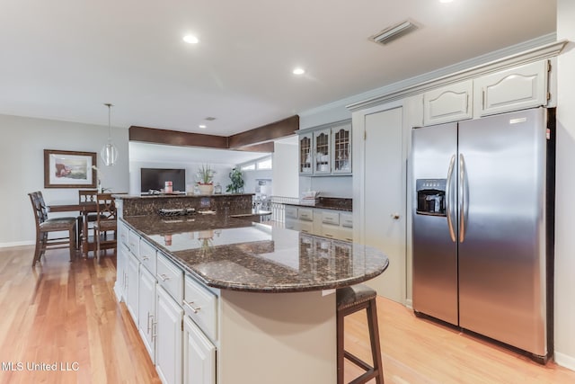 435 Christi Ln, Biloxi, MS 39531 - kitchen featuring stainless steel refrigerator with ice dispenser, light wood-type flooring, a kitchen bar, glass insert cabinets, and recessed lighting