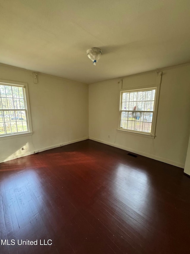 empty room featuring dark hardwood / wood-style flooring and plenty of natural light