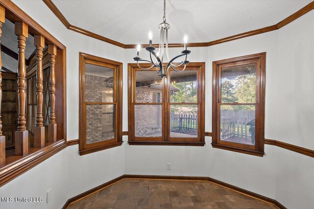 unfurnished dining area with crown molding, stone finish floor, a chandelier, and baseboards
