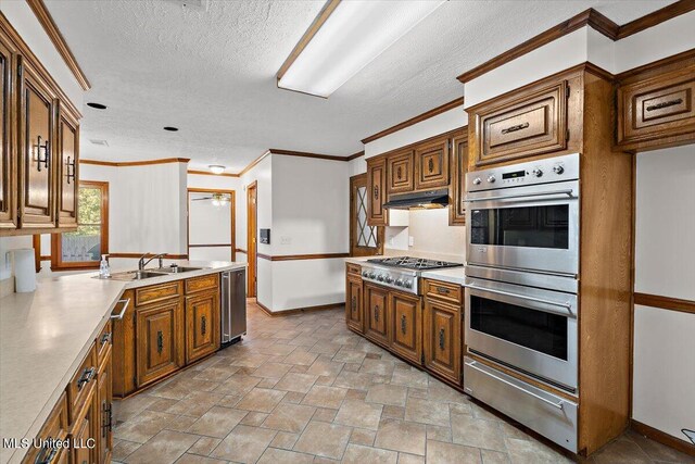 kitchen featuring stone finish floor, a sink, appliances with stainless steel finishes, under cabinet range hood, and a warming drawer