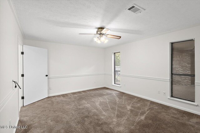 carpeted spare room with ornamental molding, baseboards, visible vents, a ceiling fan, and a textured ceiling