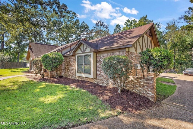view of home's exterior with fence, a yard, stucco siding, and brick siding