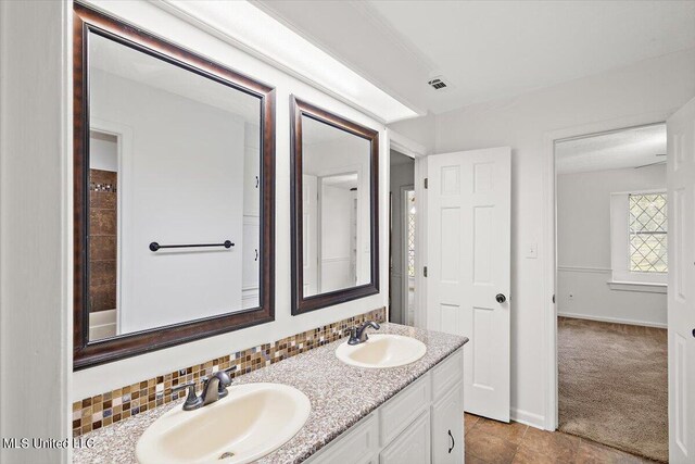 full bath with baseboards, tile patterned floors, double vanity, and a sink
