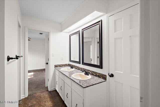 bathroom featuring double vanity, visible vents, baseboards, and a sink