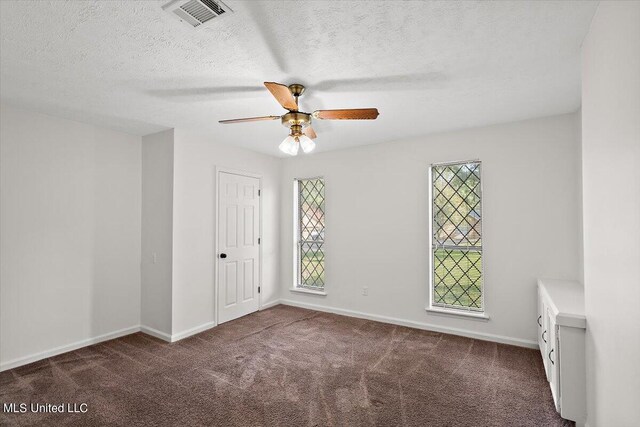 spare room featuring carpet, baseboards, visible vents, a ceiling fan, and a textured ceiling