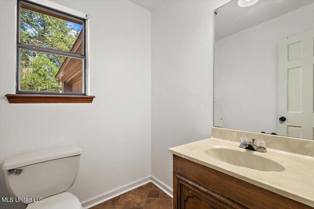 bathroom featuring toilet, vanity, and baseboards