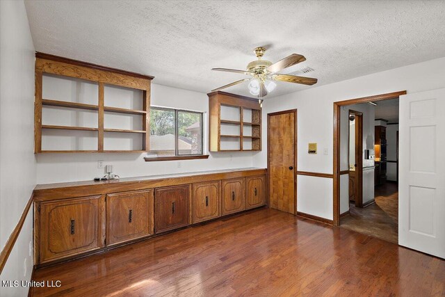 kitchen with a textured ceiling, brown cabinets, open shelves, ceiling fan, and dark wood-style floors