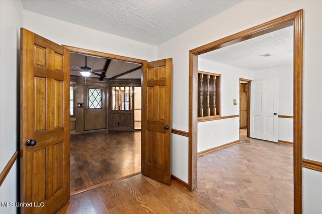 entrance foyer with a textured ceiling, hardwood / wood-style flooring, beamed ceiling, and ceiling fan