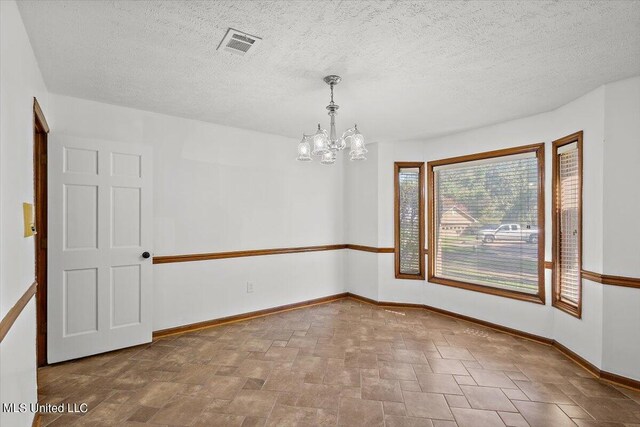 unfurnished room with baseboards, visible vents, stone finish flooring, and an inviting chandelier
