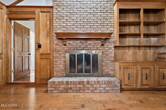 unfurnished living room featuring light hardwood / wood-style flooring and a brick fireplace