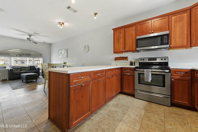 kitchen featuring visible vents, a ceiling fan, a peninsula, stainless steel appliances, and light countertops