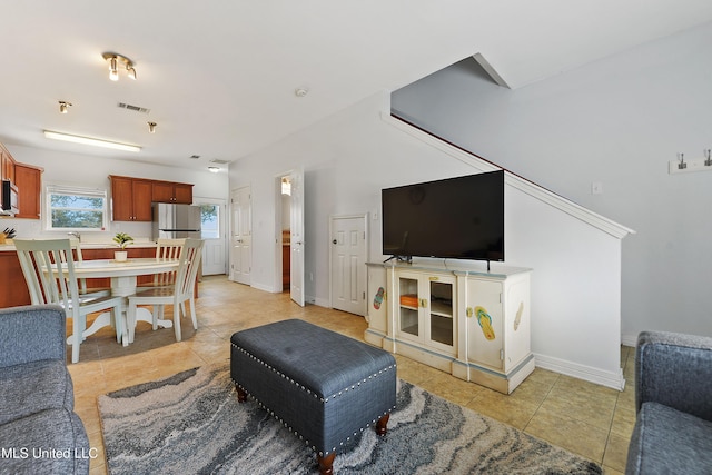 living area with light tile patterned floors, visible vents, and baseboards