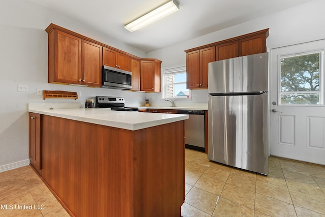 kitchen featuring appliances with stainless steel finishes, brown cabinets, light countertops, and a peninsula