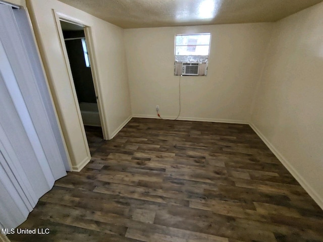 spare room with dark wood-type flooring, cooling unit, and a textured ceiling