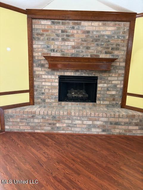 room details featuring wood-type flooring, ornamental molding, and a fireplace