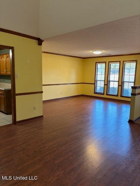 empty room with crown molding, a textured ceiling, and dark hardwood / wood-style flooring