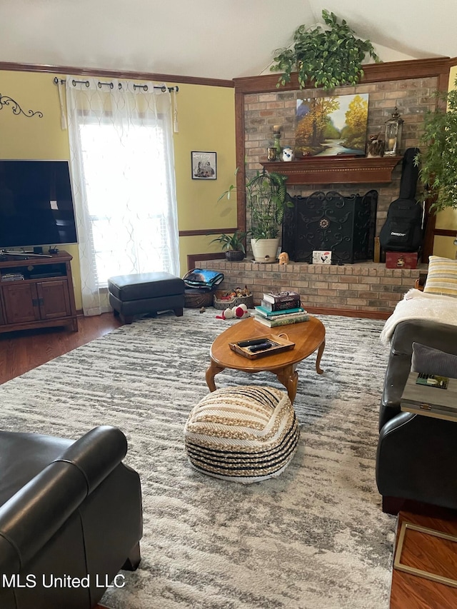 living room featuring ornamental molding, vaulted ceiling, a fireplace, and wood-type flooring