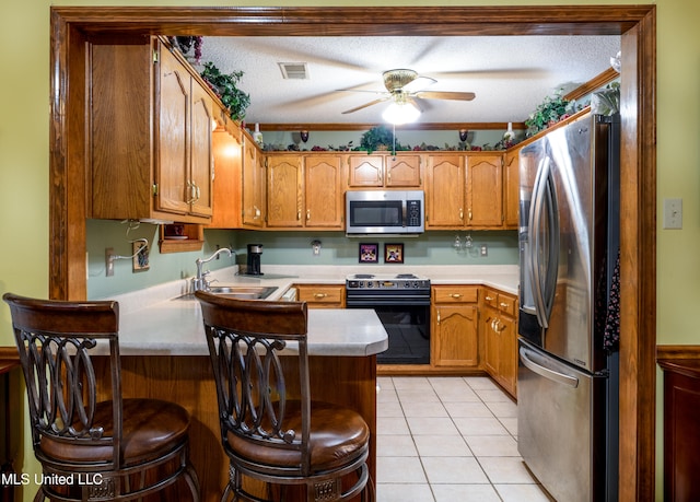 kitchen featuring a kitchen breakfast bar, appliances with stainless steel finishes, a textured ceiling, and ceiling fan