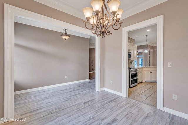 unfurnished dining area featuring a chandelier, light hardwood / wood-style floors, crown molding, and sink